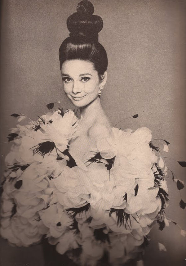 Audrey Hepburn nel famoso scatto “L’Abbraccio”, avvolta da un soffio di petali d’organza e fiori di piume nella notte Parisienne di YSL.